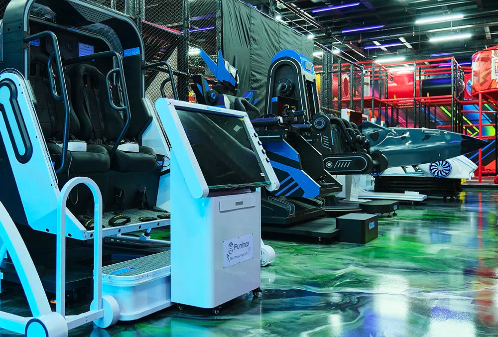 A row of futuristic virtual reality arcade machines with seats and controls stands in a neon-lit entertainment center, featuring glossy floors and vibrant colored lights in the background.