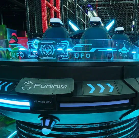 A futuristic VR arcade ride labeled "UFO" and "FuninVR" features glowing blue lights, sci-fi graphics, and sleek seats, creating a high-tech, space-themed atmosphere indoors.